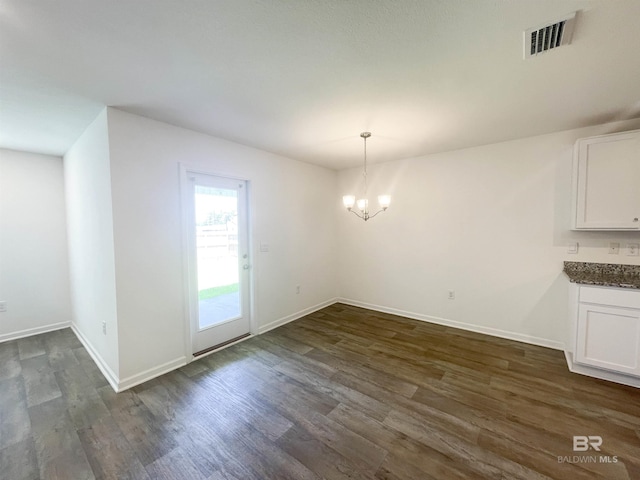 unfurnished dining area with dark wood-type flooring and an inviting chandelier