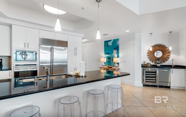 26302 Perdido Beach Blvd Unit D708, Orange Beach, AL 36561 - kitchen with beverage cooler, built in appliances, dark countertops, white cabinetry, and pendant lighting