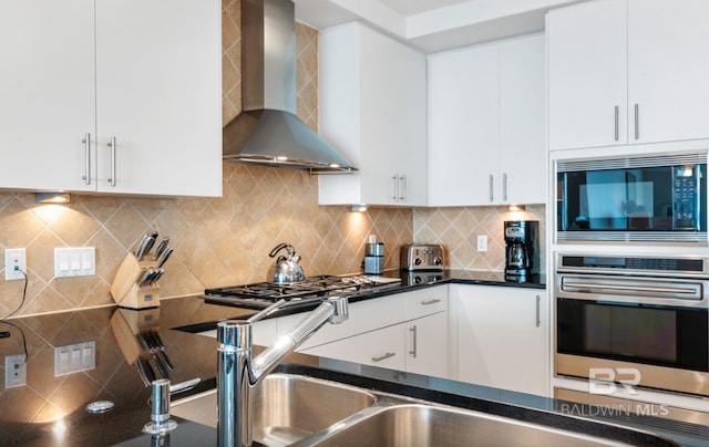 26302 Perdido Beach Blvd Unit D708, Orange Beach, AL 36561 - kitchen featuring wall chimney range hood, stainless steel appliances, tasteful backsplash, dark countertops, and white cabinets