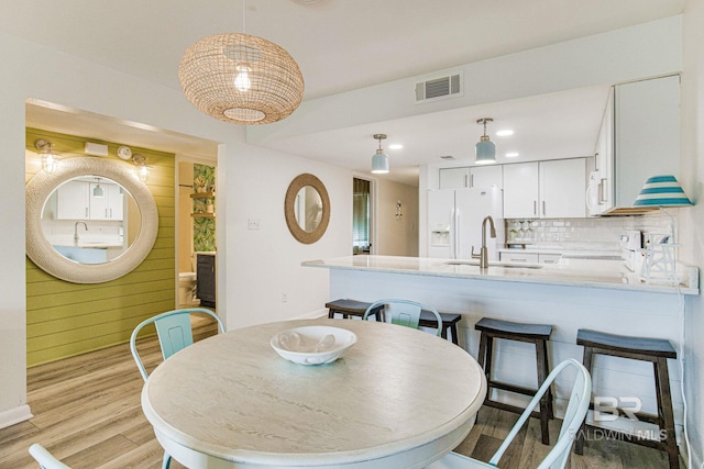 dining area featuring sink, light hardwood / wood-style flooring, and wood walls