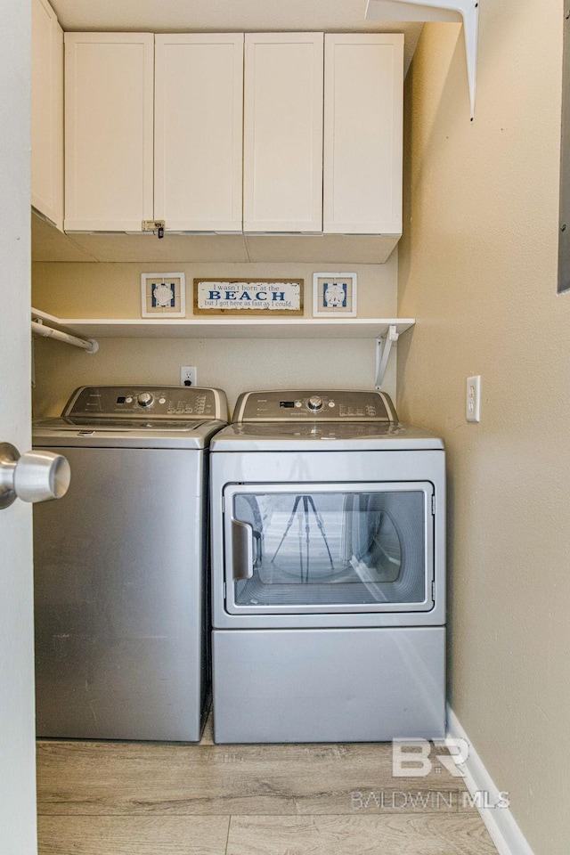 laundry room with cabinets, light hardwood / wood-style flooring, and washer and dryer