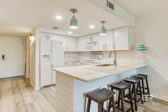 kitchen featuring sink, pendant lighting, white appliances, light hardwood / wood-style floors, and white cabinets