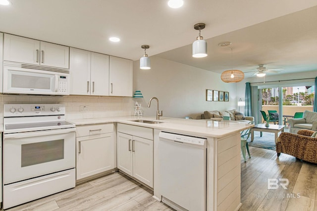 kitchen with pendant lighting, sink, white appliances, white cabinetry, and kitchen peninsula