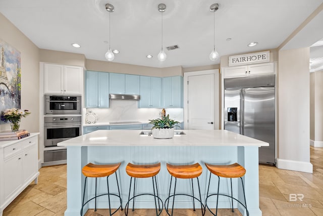 kitchen featuring light countertops, appliances with stainless steel finishes, a kitchen bar, and visible vents