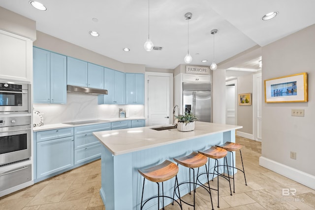 kitchen featuring a sink, a breakfast bar area, blue cabinets, a warming drawer, and stainless steel appliances