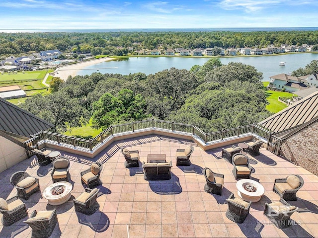 view of patio with a water view and an outdoor living space with a fire pit