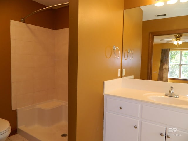 bathroom featuring ceiling fan, vanity, toilet, and tiled shower