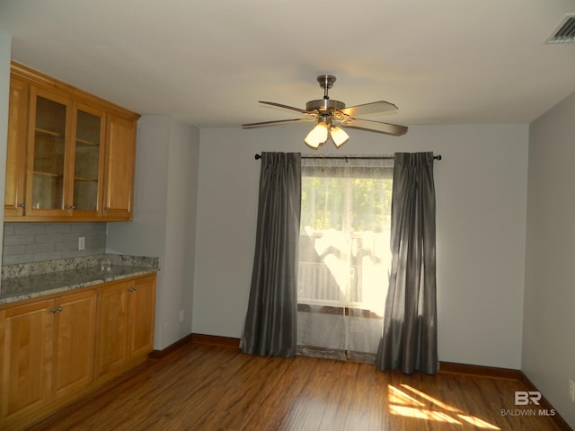 kitchen with decorative backsplash, wood-type flooring, light stone counters, and ceiling fan