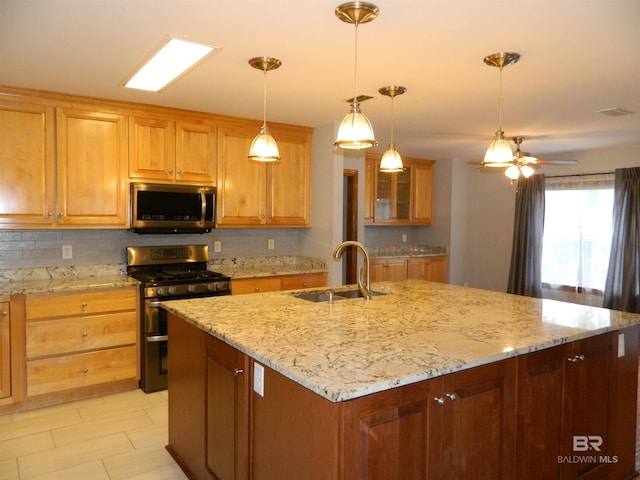 kitchen featuring sink, decorative light fixtures, a center island with sink, stainless steel appliances, and light stone countertops