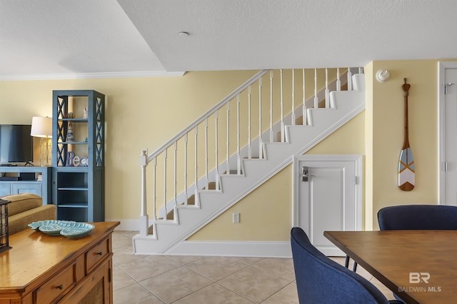 interior space with tile patterned flooring, baseboards, a textured ceiling, and ornamental molding