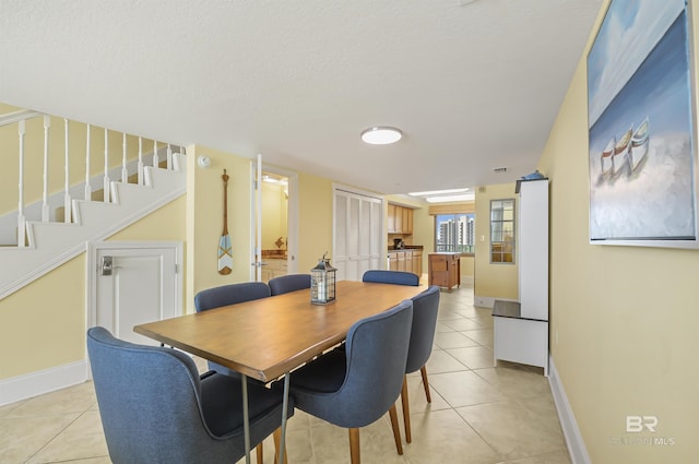 dining space with a textured ceiling, stairway, baseboards, and light tile patterned floors