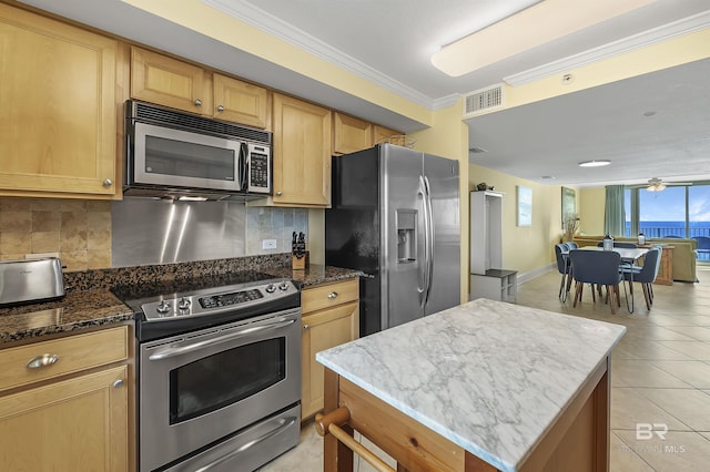 kitchen featuring stainless steel appliances, dark stone counters, crown molding, and decorative backsplash