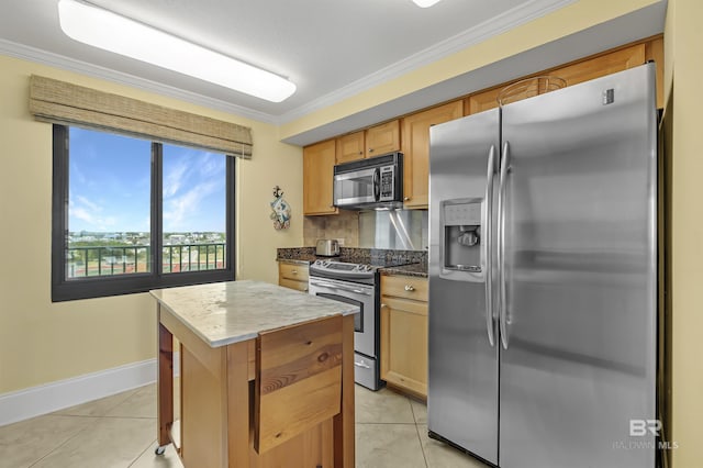 kitchen with stainless steel appliances, a kitchen island, ornamental molding, and light tile patterned floors