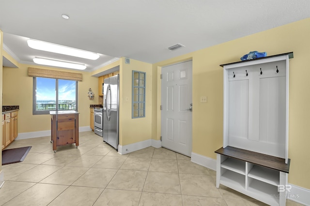 kitchen with light tile patterned floors, visible vents, baseboards, appliances with stainless steel finishes, and ornamental molding