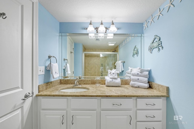 full bathroom with a textured ceiling, a stall shower, and vanity