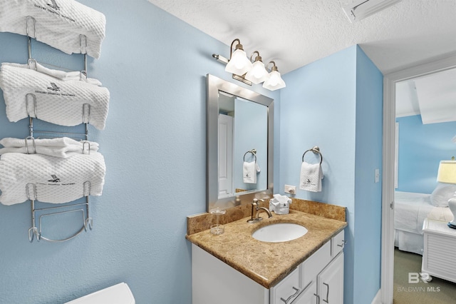 ensuite bathroom with a textured wall, toilet, ensuite bathroom, a textured ceiling, and vanity