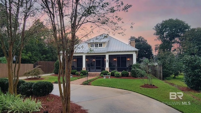 view of front of property featuring a sunroom and a yard