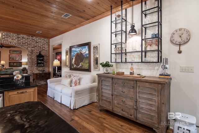 living room with dark wood-type flooring, wooden ceiling, brick wall, and indoor bar