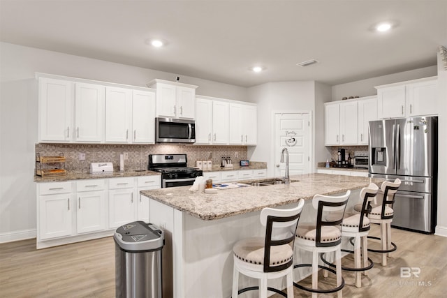 kitchen with white cabinetry, appliances with stainless steel finishes, sink, and an island with sink