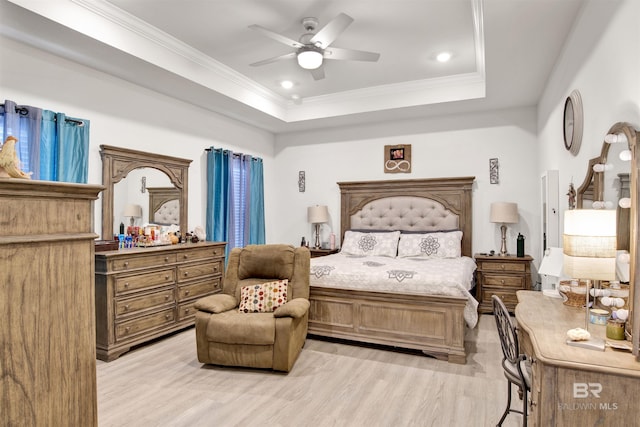 bedroom featuring crown molding, ceiling fan, light wood-type flooring, and a tray ceiling