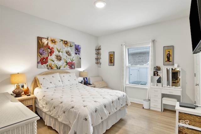 bedroom with light wood finished floors and baseboards