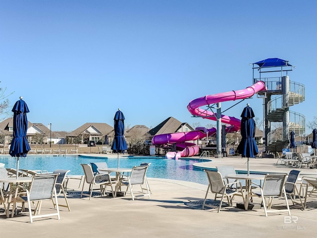 pool featuring fence, a water slide, and a patio