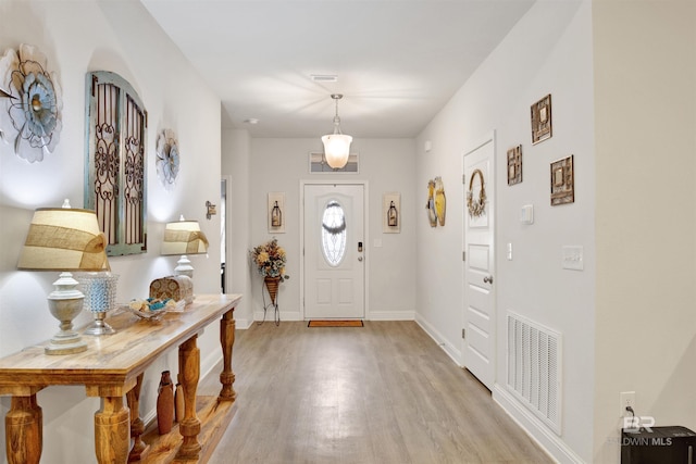 foyer with light wood-style flooring, visible vents, and baseboards