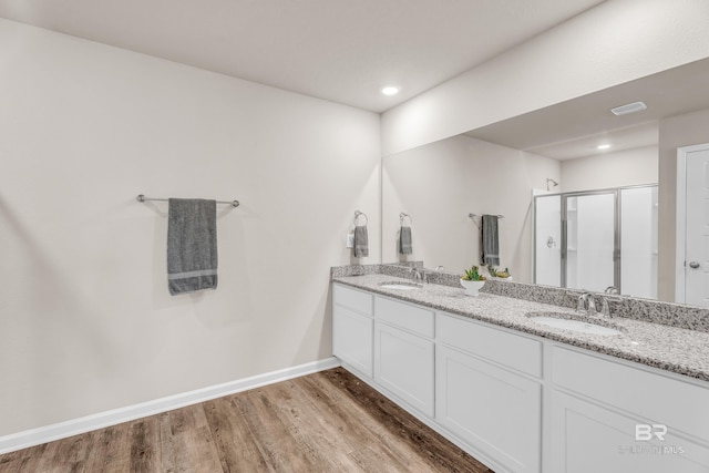 bathroom featuring a stall shower, a sink, baseboards, and wood finished floors