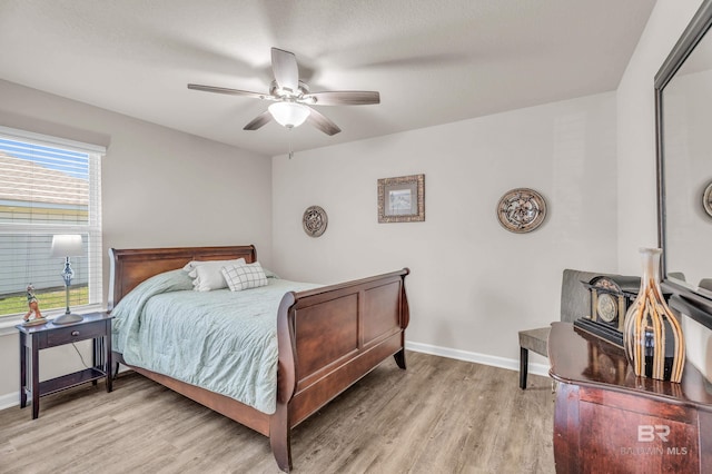 bedroom with light wood-style floors, ceiling fan, and baseboards