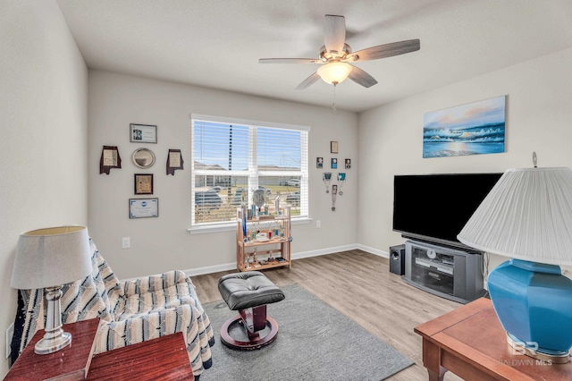 living room with wood finished floors, a ceiling fan, and baseboards