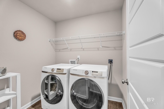 washroom with laundry area, baseboards, wood finished floors, and washing machine and clothes dryer