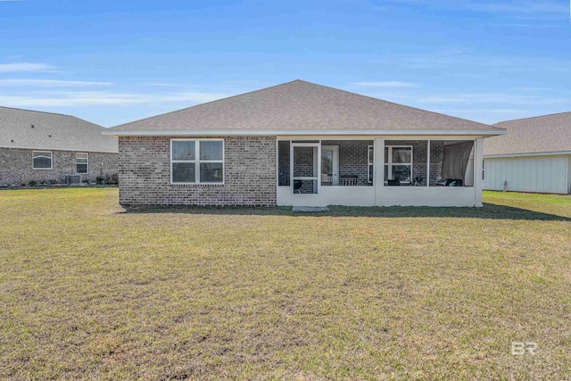 rear view of property with a yard, a sunroom, and brick siding