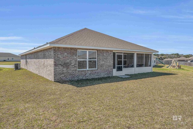 back of house with a yard, central AC unit, a playground, and brick siding