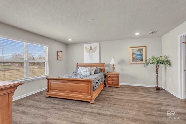 bedroom with light wood-style flooring, visible vents, and baseboards