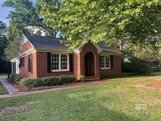 view of front of home featuring brick siding, a shingled roof, and a front yard