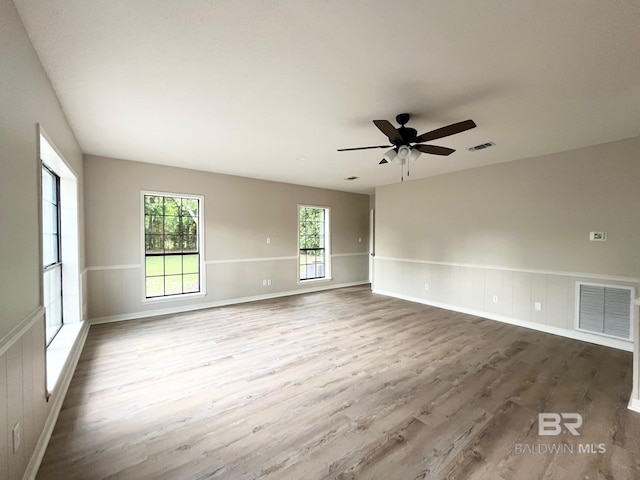 unfurnished room featuring a wainscoted wall, a ceiling fan, wood finished floors, and visible vents