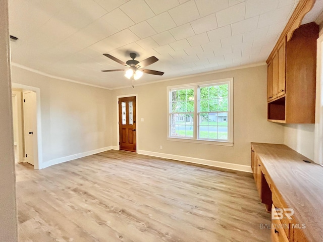 unfurnished living room featuring crown molding, a ceiling fan, light wood-style floors, and baseboards