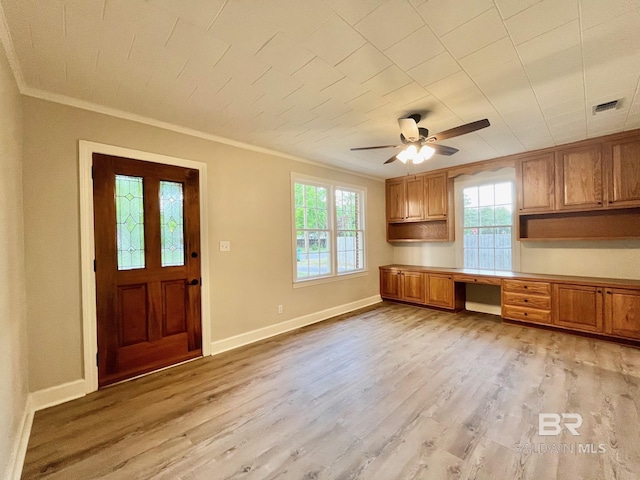 interior space featuring a ceiling fan, ornamental molding, built in study area, and plenty of natural light