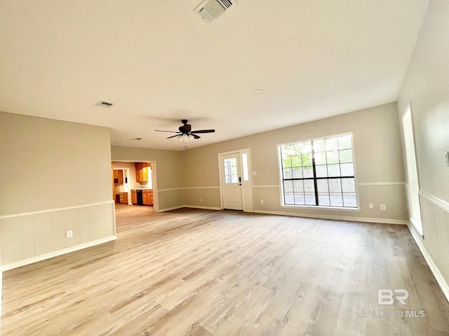 spare room with light wood-style floors, baseboards, ceiling fan, and visible vents
