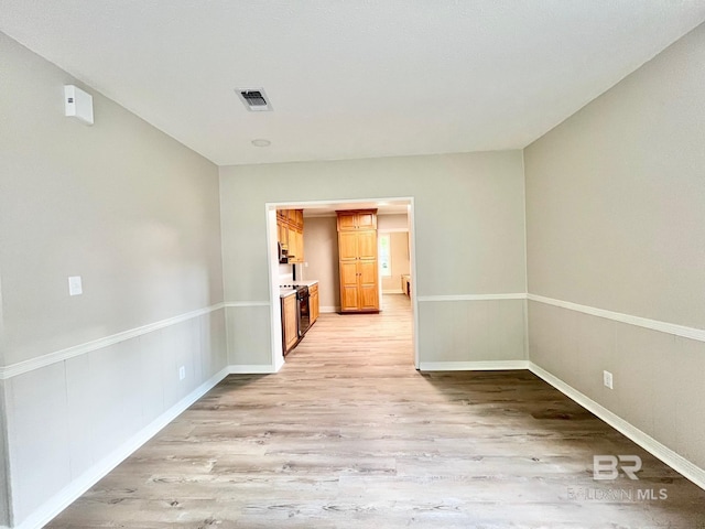 spare room with baseboards, visible vents, and light wood-style floors