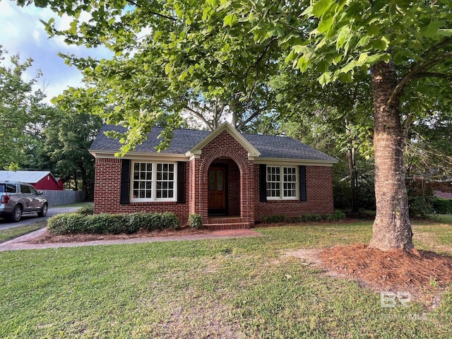 view of front of home featuring roof with shingles, a front lawn, and brick siding
