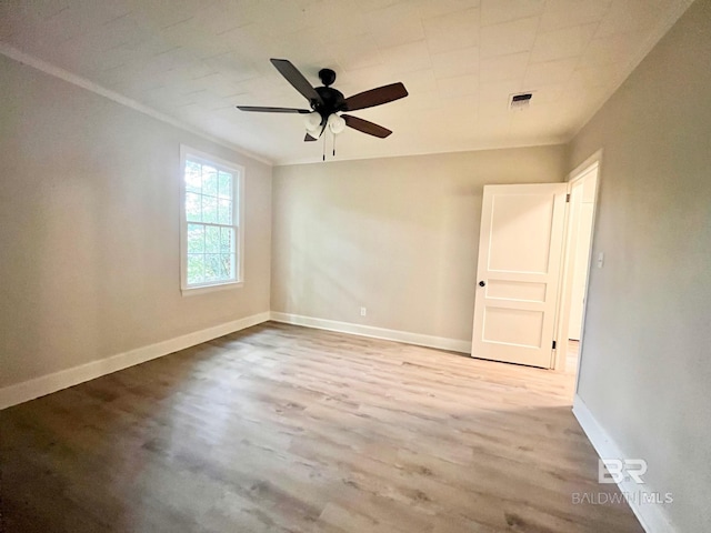 unfurnished room with ceiling fan, visible vents, wood finished floors, baseboards, and ornamental molding