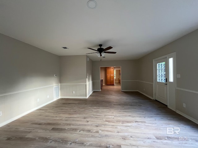 unfurnished living room featuring a ceiling fan, wood finished floors, and visible vents