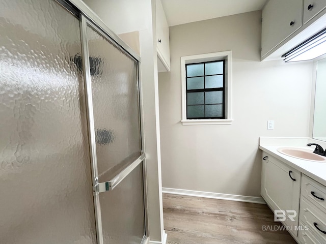 full bath featuring vanity, baseboards, wood finished floors, and a shower stall