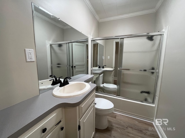 bathroom featuring vanity, toilet, combined bath / shower with glass door, wood finished floors, and ornamental molding