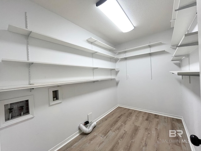 clothes washing area featuring baseboards, laundry area, hookup for a washing machine, and wood finished floors