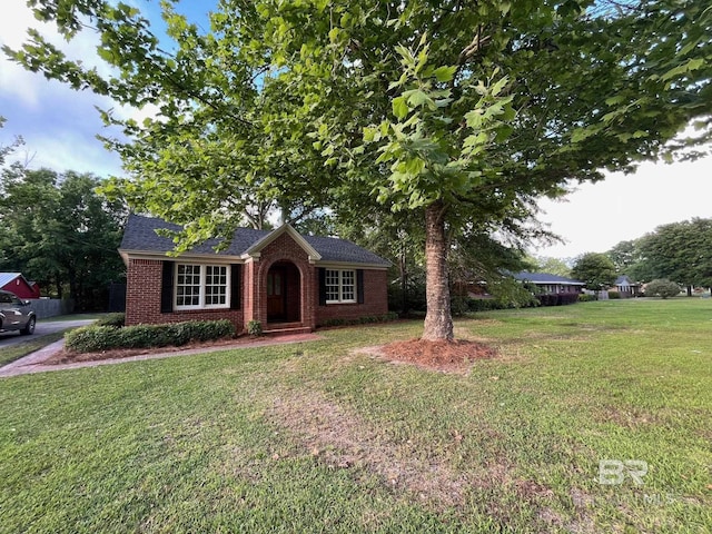 view of front of house with brick siding, a shingled roof, and a front lawn
