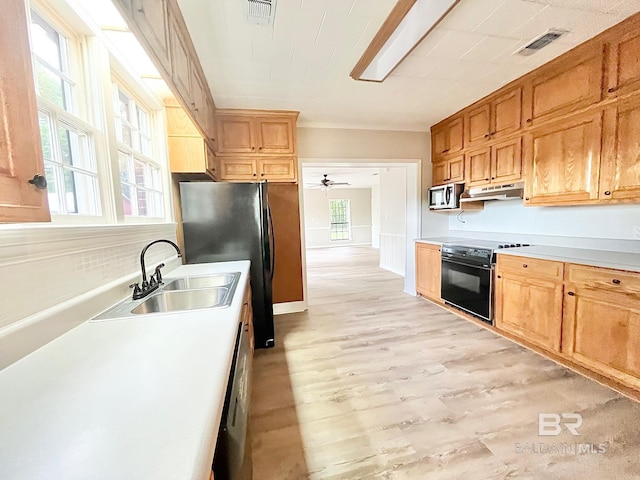 kitchen featuring under cabinet range hood, black appliances, a sink, and visible vents
