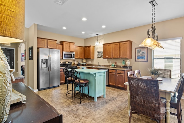 kitchen with sink, a center island, hanging light fixtures, a breakfast bar, and appliances with stainless steel finishes