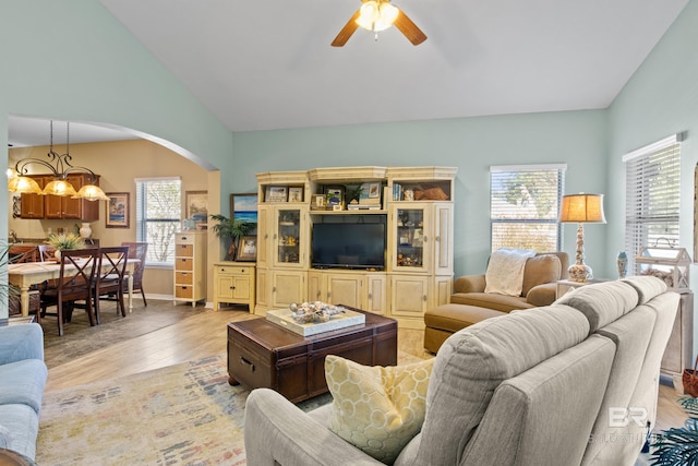 living room with plenty of natural light, wood-type flooring, ceiling fan with notable chandelier, and vaulted ceiling